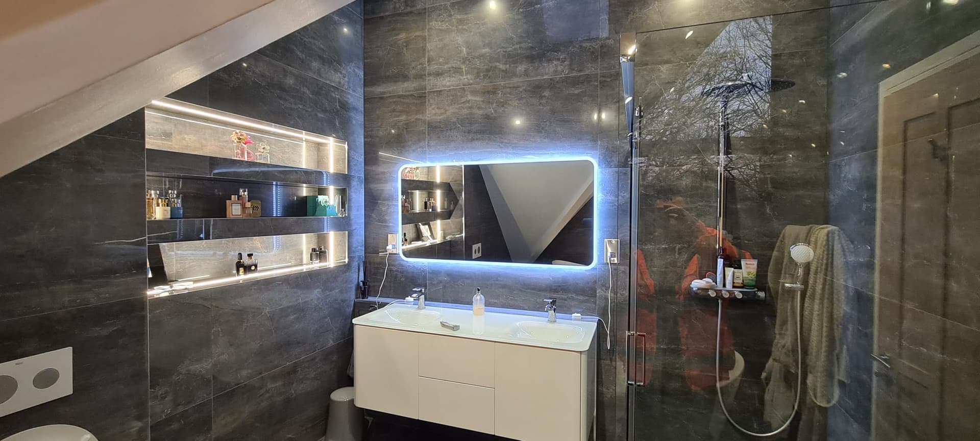A finished stone bathroom with backlit shelving and a walk-in shower in Romsey