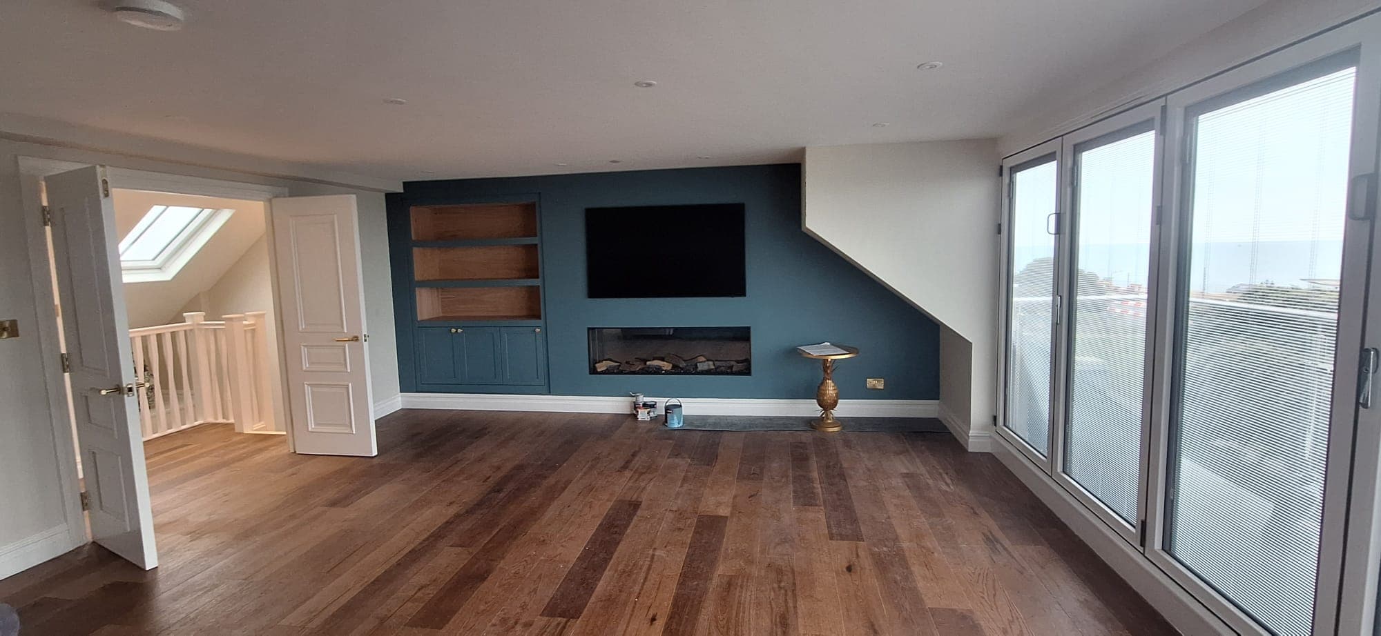 A finished loft living room with a bespoke media wall and sea view in Winchester